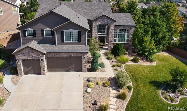 view of front of property featuring a garage, driveway, a shingled roof, stone siding, and fence