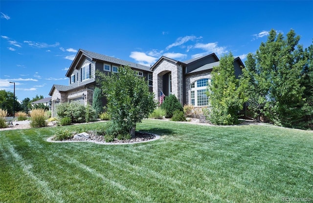 view of front of property featuring stone siding, an attached garage, and a front lawn