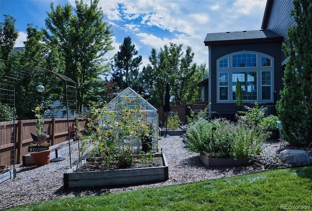 view of yard with an outbuilding, a greenhouse, a vegetable garden, and fence