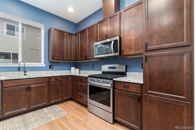 7808 W 43rd Pl, Wheat Ridge, CO 80033 - kitchen with stainless steel appliances, a sink, light wood-style floors, light stone countertops, and dark brown cabinetry