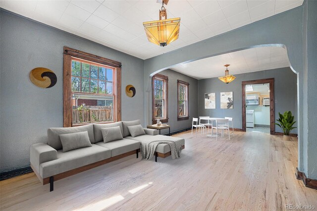 4635 Teller St, Wheat Ridge, CO 80033 - living room featuring arched walkways, light wood finished floors, and baseboards