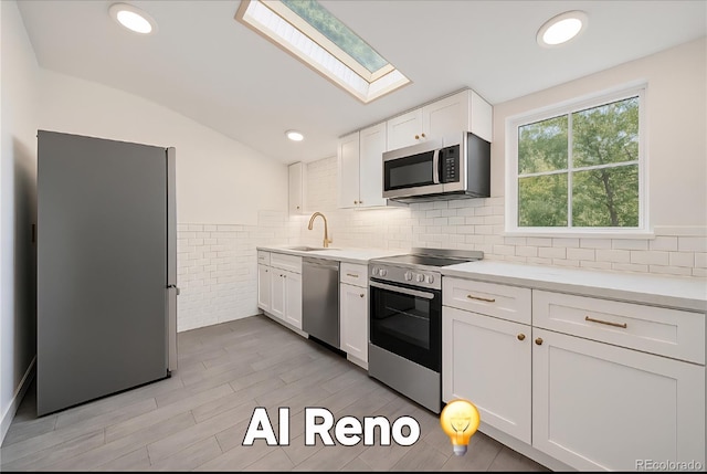 4635 Teller St, Wheat Ridge, CO 80033 - kitchen with appliances with stainless steel finishes, a skylight, a sink, white cabinetry, and light countertops