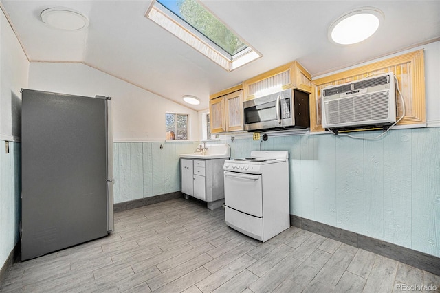 4635 Teller St, Wheat Ridge, CO 80033 - kitchen featuring appliances with stainless steel finishes, a wall mounted AC, a skylight, light wood-type flooring, and vaulted ceiling