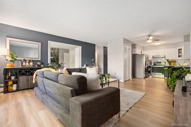 7040 E Girard Ave Unit 207, Denver, CO 80224 - living room featuring ceiling fan, light wood-style flooring, and a textured ceiling