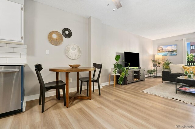 7040 E Girard Ave Unit 207, Denver, CO 80224 - dining area featuring light wood finished floors, baseboards, a fireplace, and ceiling fan