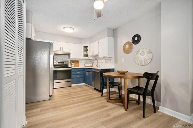 7040 E Girard Ave Unit 207, Denver, CO 80224 - kitchen with stainless steel appliances, under cabinet range hood, blue cabinets, a textured ceiling, and tasteful backsplash