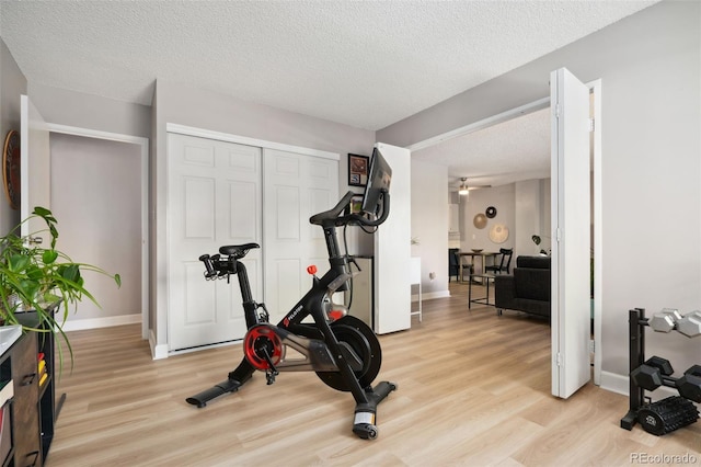 7040 E Girard Ave Unit 207, Denver, CO 80224 - exercise room with light wood-style flooring, baseboards, and a textured ceiling