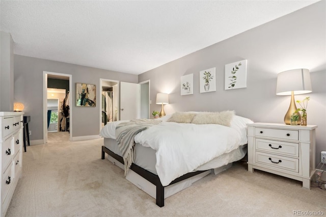 7040 E Girard Ave Unit 207, Denver, CO 80224 - bedroom featuring light carpet, a walk in closet, baseboards, and a closet