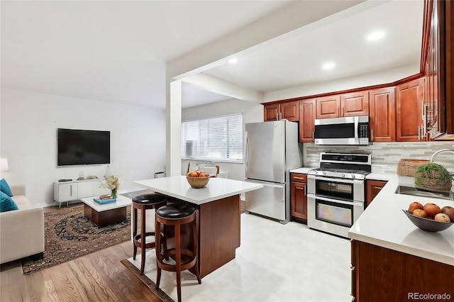 kitchen with sink, a center island, appliances with stainless steel finishes, a kitchen breakfast bar, and decorative backsplash