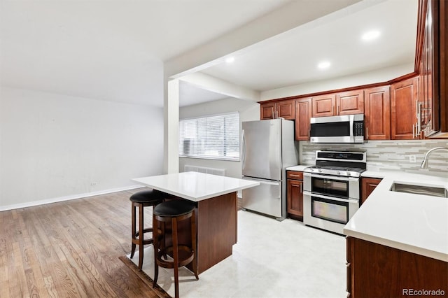 kitchen with appliances with stainless steel finishes, tasteful backsplash, sink, a kitchen breakfast bar, and a center island