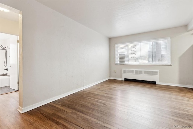 unfurnished living room featuring wood-type flooring and radiator heating unit