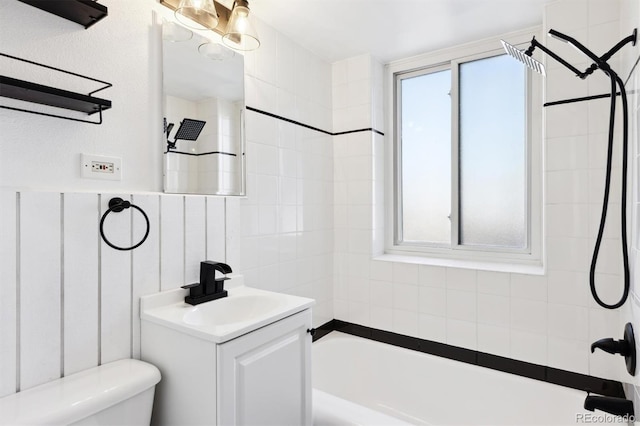 full bathroom featuring vanity, tiled shower / bath, and toilet