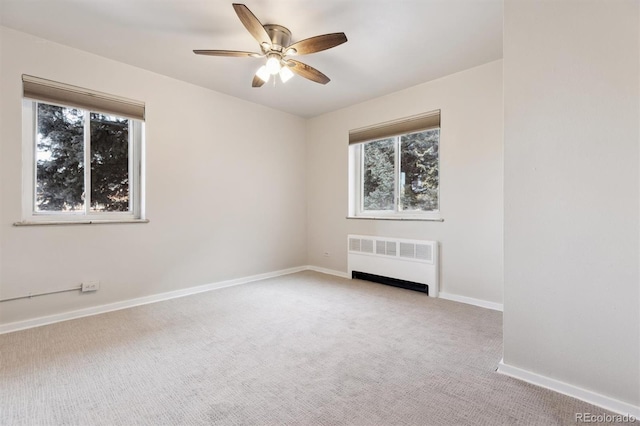 carpeted empty room featuring radiator heating unit and ceiling fan