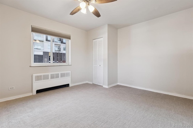 empty room with ceiling fan, radiator heating unit, and carpet floors