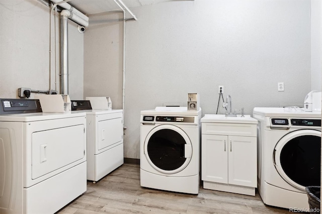 laundry area featuring light hardwood / wood-style floors, sink, cabinets, and independent washer and dryer