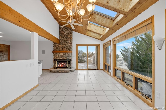 unfurnished living room featuring a skylight, ceiling fan, a stone fireplace, light tile patterned floors, and wood ceiling