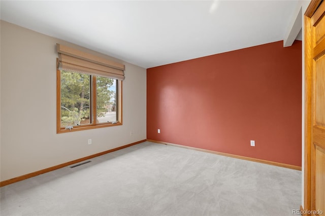 spare room with lofted ceiling with beams and light colored carpet