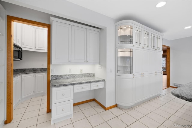 kitchen featuring built in desk, white cabinets, and light tile patterned flooring