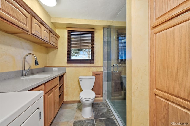 bathroom featuring washer / dryer, vanity, toilet, and a shower with door