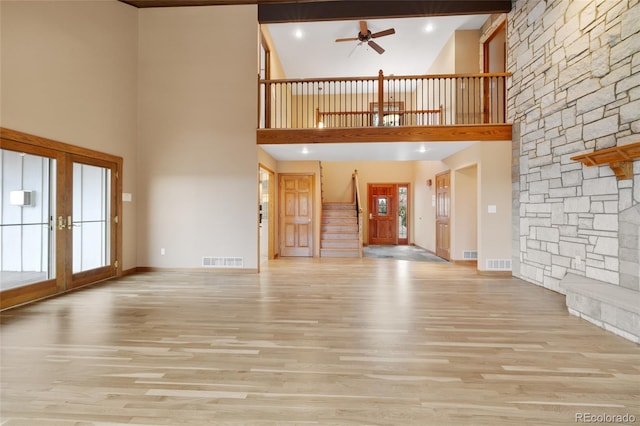 unfurnished living room featuring ceiling fan, a high ceiling, and light hardwood / wood-style flooring