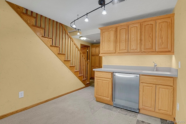 kitchen with dishwasher, light brown cabinetry, track lighting, and sink