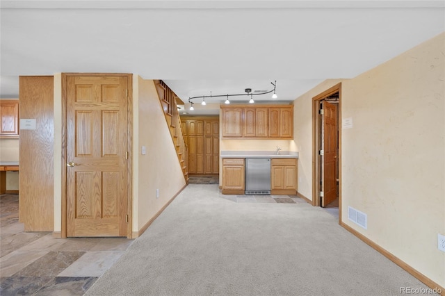 kitchen with stainless steel dishwasher, light carpet, and light brown cabinetry