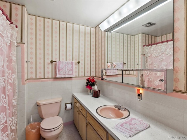 3018 S Depew St, Denver, CO 80227 - bathroom with vanity, toilet, wainscoting, wallpapered walls, and tile walls