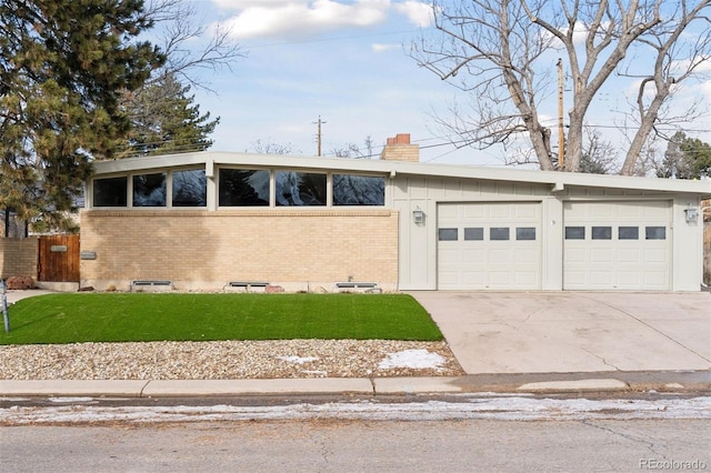 mid-century home featuring driveway, a garage, a chimney, and brick siding