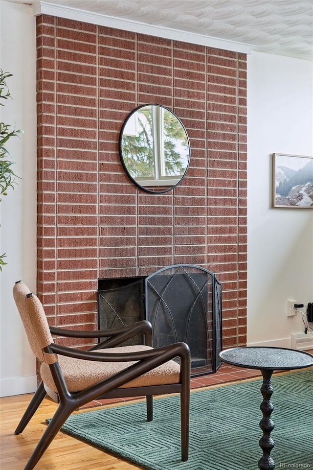 sitting room featuring a fireplace, baseboards, and wood finished floors