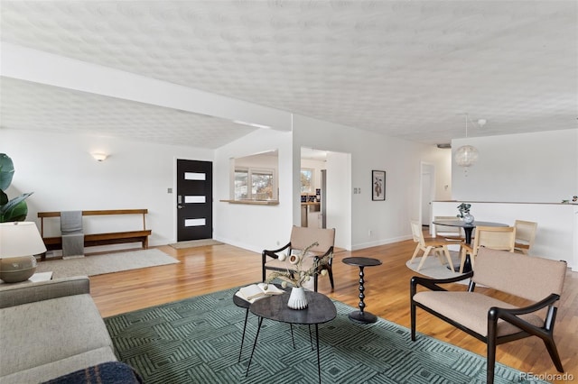 living room with light wood-type flooring, a textured ceiling, and baseboards