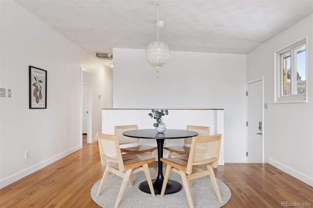 dining area featuring baseboards, visible vents, and light wood finished floors