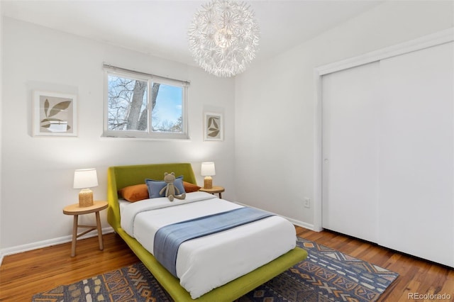 bedroom featuring a notable chandelier, a closet, wood finished floors, and baseboards