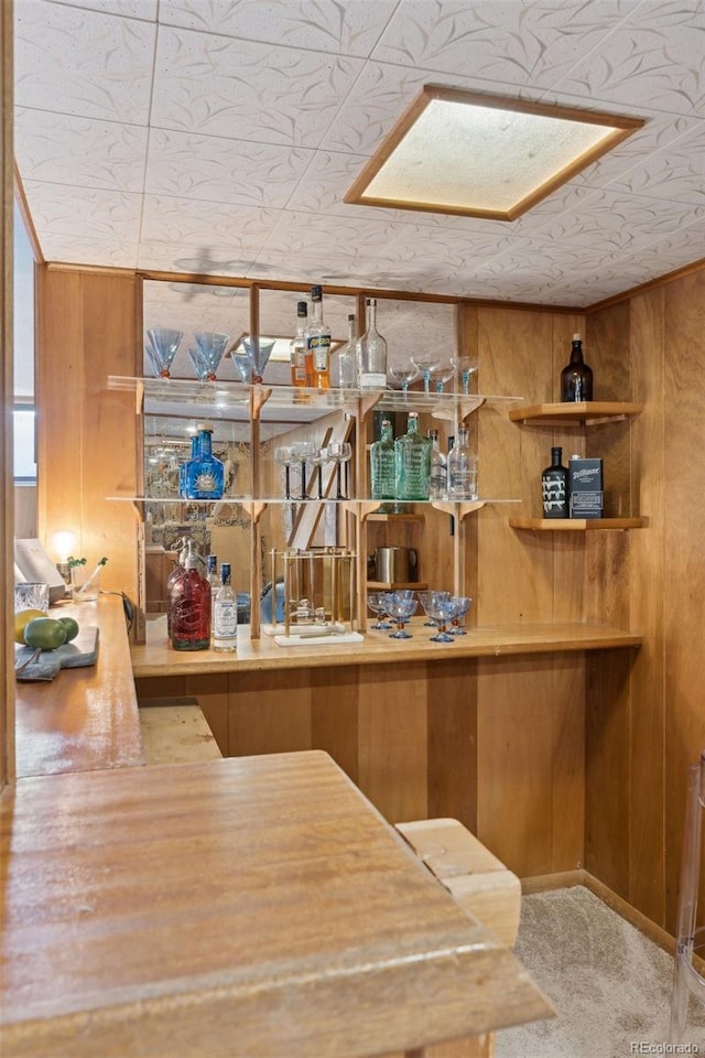 bar with a dry bar, wood walls, and carpet flooring