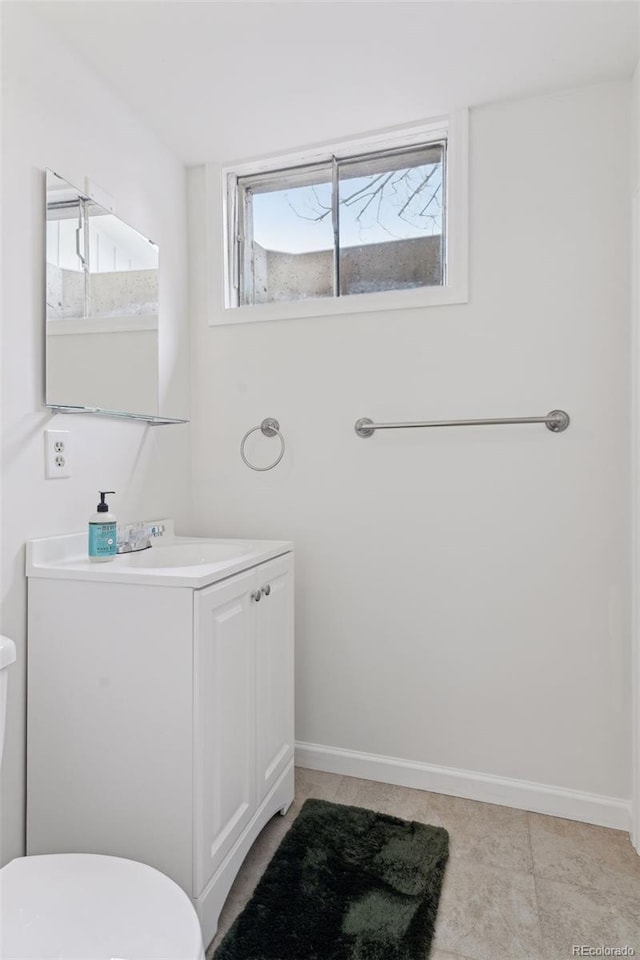 bathroom with baseboards, vanity, and toilet