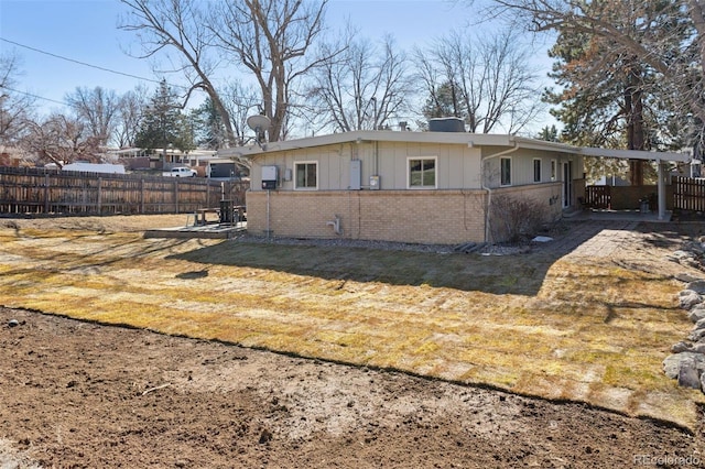 exterior space with brick siding, fence, and a lawn