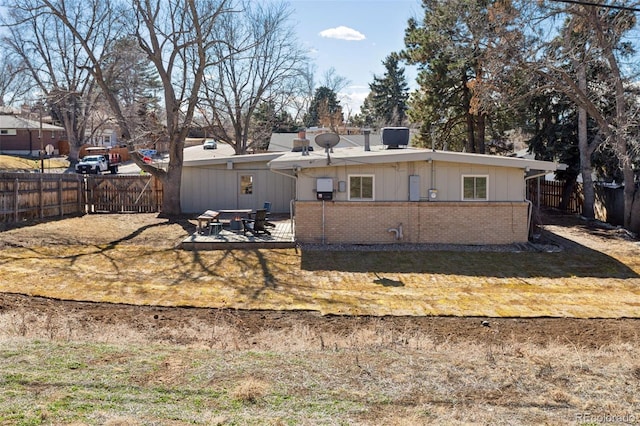 view of front of home featuring brick siding, a patio, and a fenced backyard