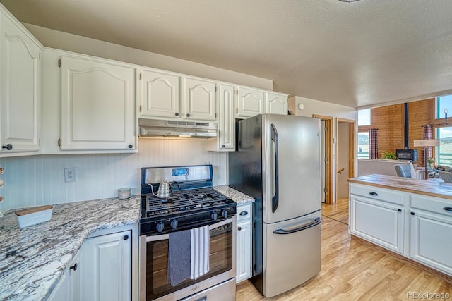 895 Acorn Rd, Cotopaxi, CO 81223 - kitchen with stainless steel appliances, under cabinet range hood, light wood-style flooring, white cabinetry, and light stone countertops