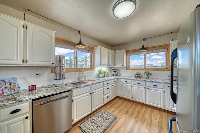 895 Acorn Rd, Cotopaxi, CO 81223 - kitchen with stainless steel appliances, light wood-style floors, white cabinetry, light stone countertops, and a textured ceiling