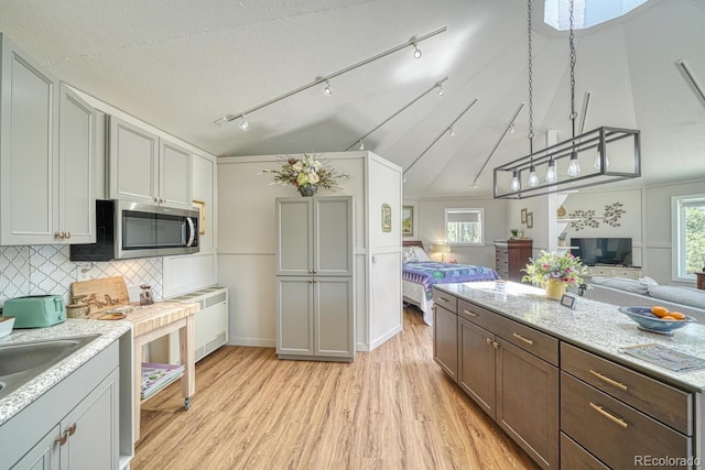 895 Acorn Rd, Cotopaxi, CO 81223 - kitchen featuring stainless steel microwave, open floor plan, light wood finished floors, backsplash, and hanging light fixtures