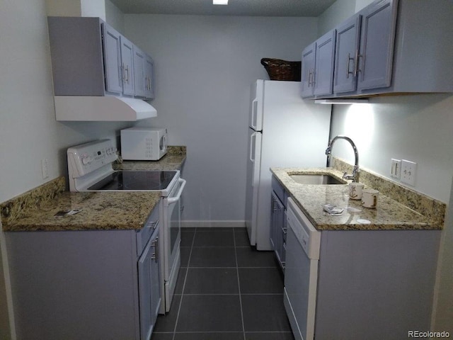 kitchen featuring white appliances, a sink, dark tile patterned flooring, range hood, and baseboards