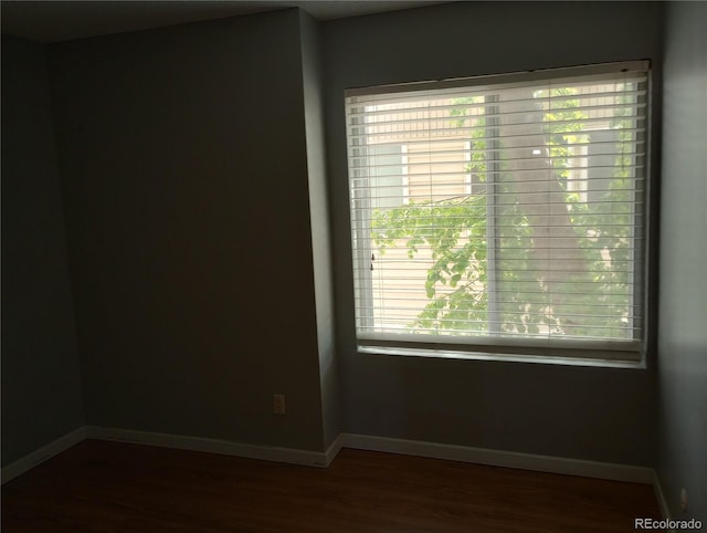 spare room featuring wood finished floors, plenty of natural light, and baseboards