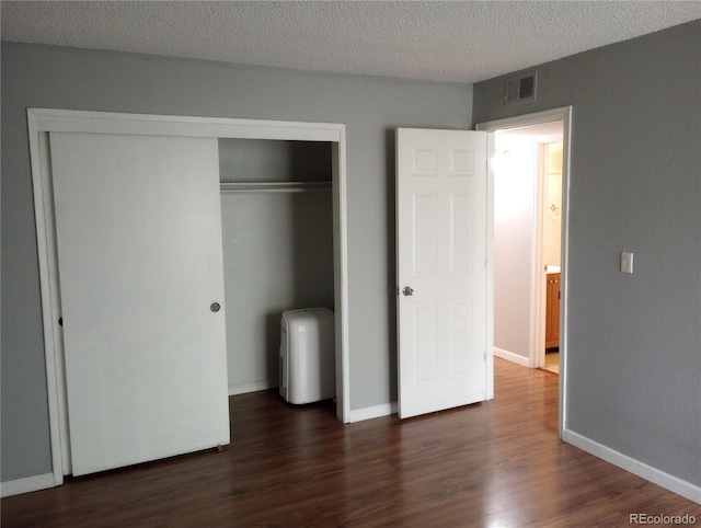 unfurnished bedroom featuring dark wood finished floors, a closet, a textured ceiling, and baseboards