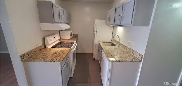 kitchen with white appliances, exhaust hood, a sink, dark tile patterned flooring, and baseboards
