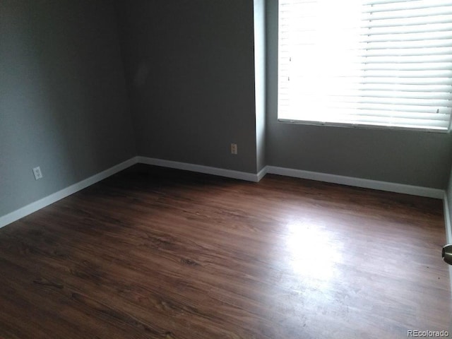 spare room featuring dark wood-style flooring and baseboards