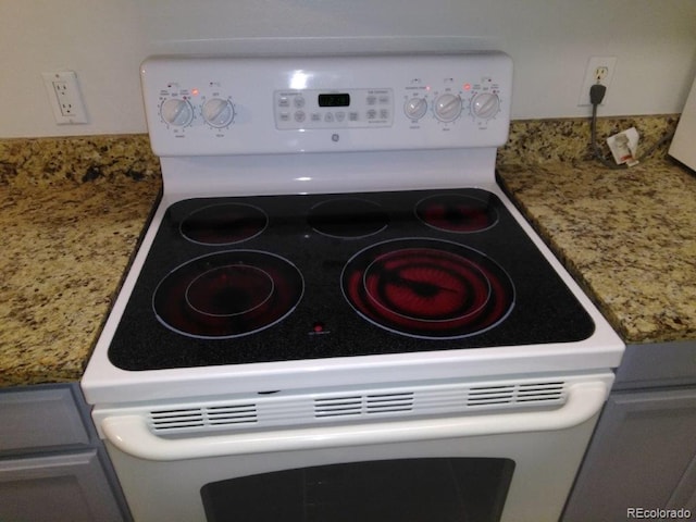 kitchen view of white range with electric stovetop and light stone countertops