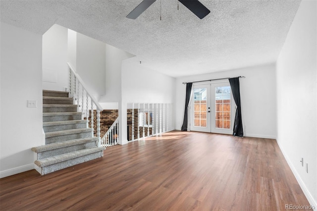 unfurnished living room with wood finished floors, a ceiling fan, baseboards, french doors, and stairway