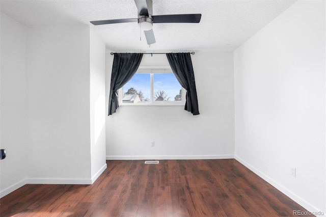 spare room featuring dark wood-style floors, visible vents, a textured ceiling, and baseboards