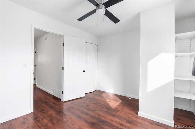 unfurnished bedroom with dark wood-style floors, ceiling fan, baseboards, and a closet