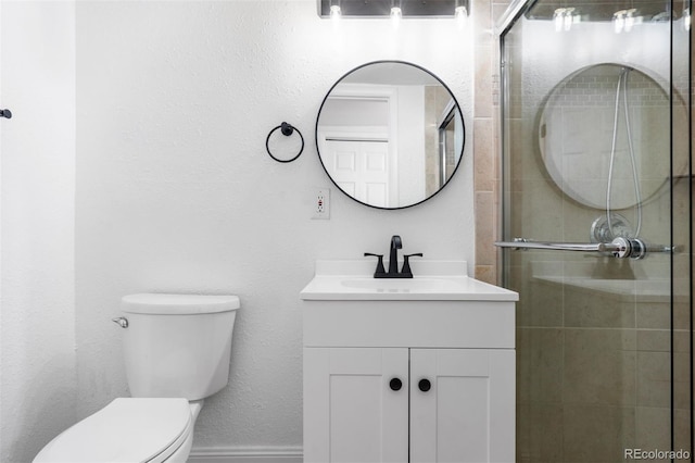 bathroom with toilet, baseboards, a tile shower, and vanity