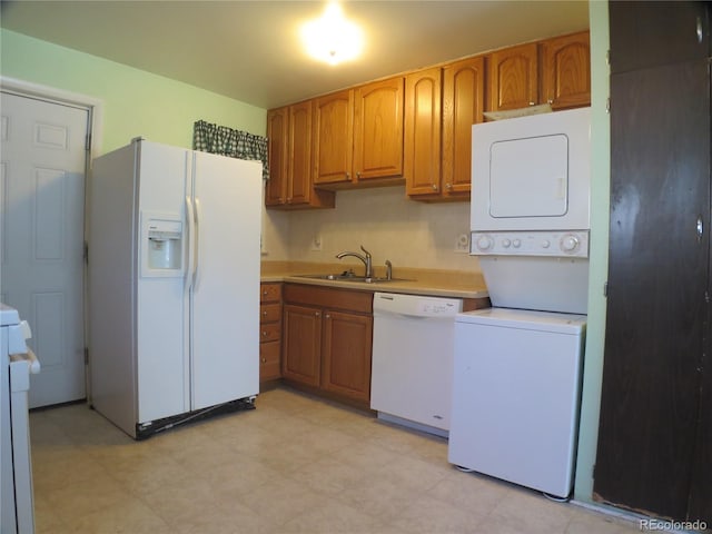 875 Kenton St, Aurora, CO 80010 - kitchen with white appliances, stacked washer / drying machine, and brown cabinetry